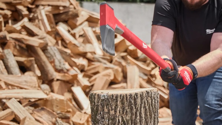 A worker swinging a Milwaukee splitting axe at a wood round.