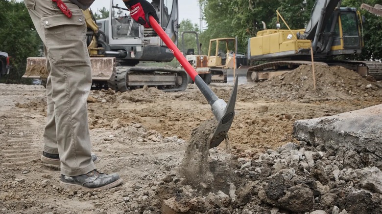 A worker digging rubble with Milwaukee pick mattock.