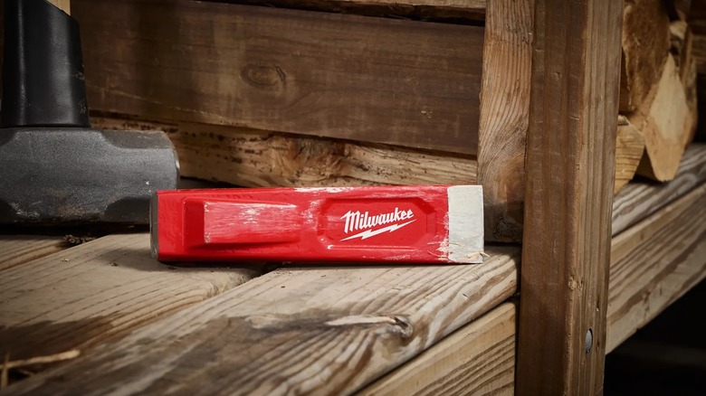 A Milwaukee splitting wedge resting on a wooden shelf.