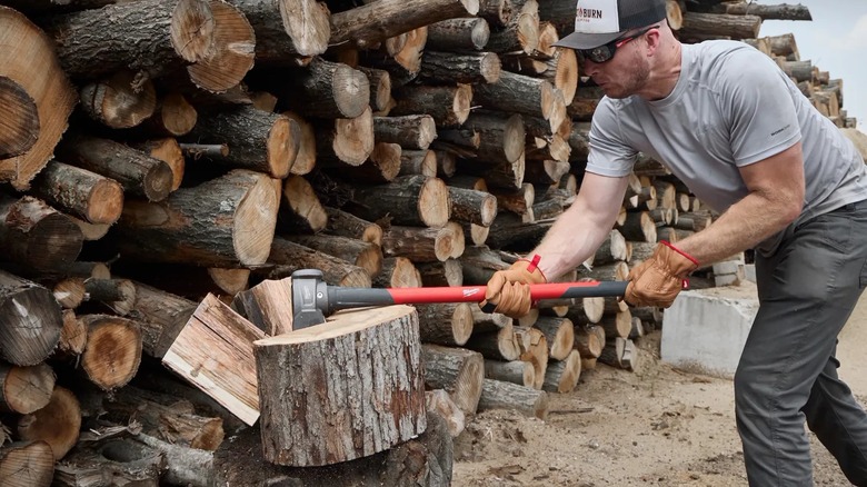 A worker chopping wood with Milwaukee splitting maul.