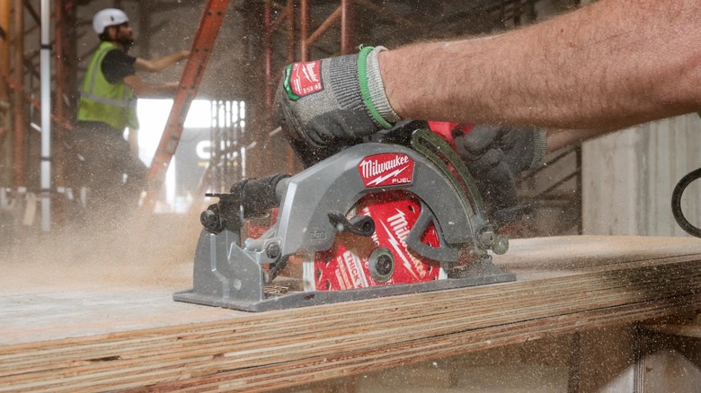 A person using a Milwaukee circular saw on wood.