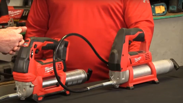 Milwaukee M12 and M18 grease guns on workshop table