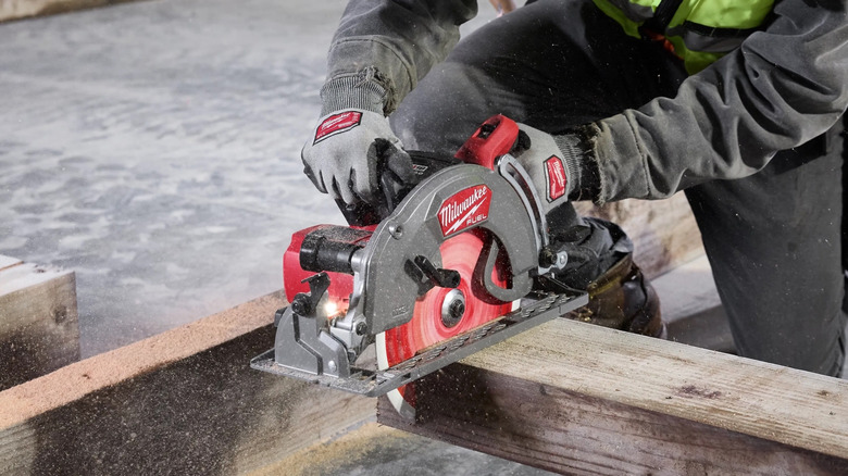 worker using a Milwaukee M18 10-1/4&Prime; Rear Handle Circular Saw to cut a wood beam