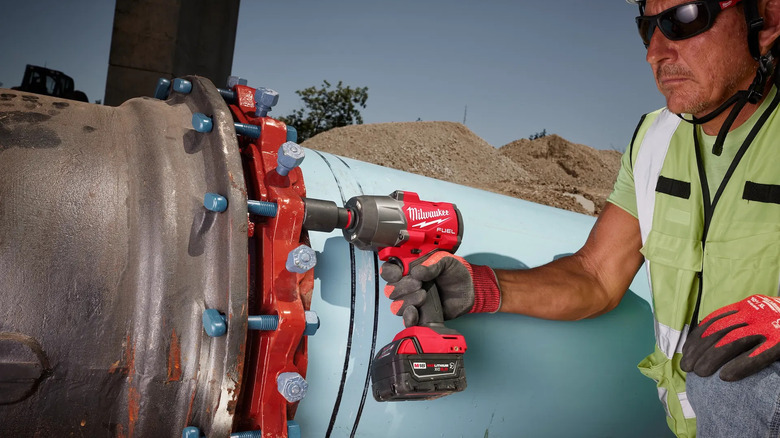 A worker using a Milwaukee M18 Fuel impact wrench on a large pipe.