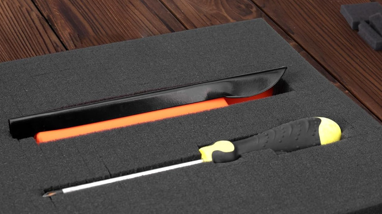 A screwdriver and another tool inside a foam insert on a table.