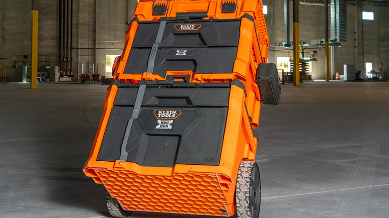 A worker carts a stack of Klein Tools cases via the Modbox Rolling Drawer