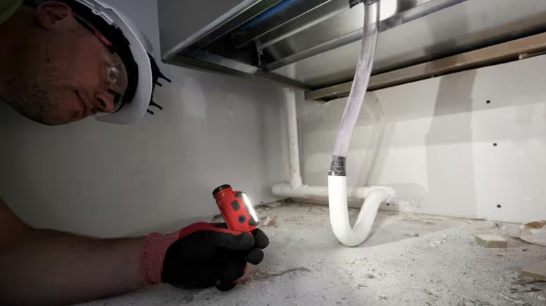Person using a flashlight to see under a sink