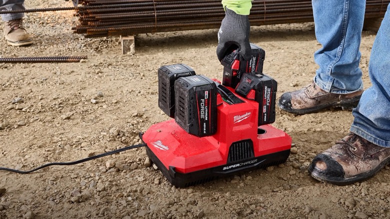 Person bending down to grab a battery from a M18 & M12 Four Bay Simultaneous Super Charger