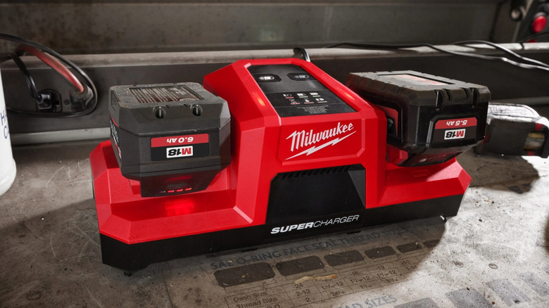 Milwaukee Super Charger on floor with two M18 batteries inserted