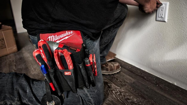 A person wearing a Milwaukee tool pouch.