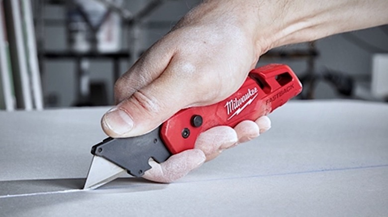 Person using a Milwaukee Fastback Utility Knife