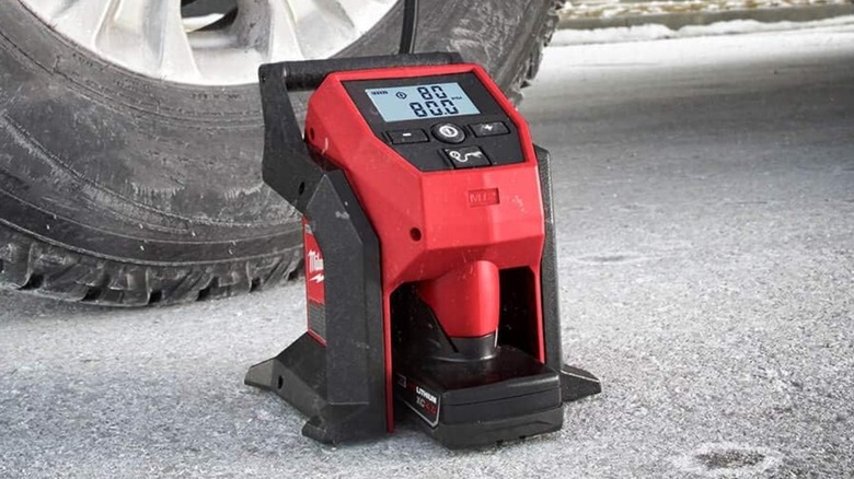 Milwaukee M12 Portable Inflator on ground beside tire
