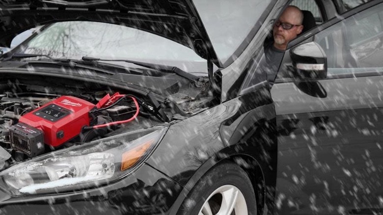 Person charging a car battery with Milwaukee Hot Shot jump starter