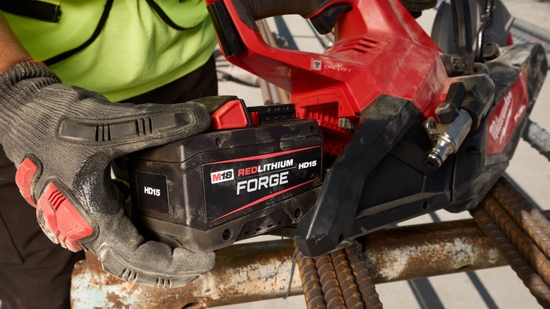 A person inserting a Milwaukee battery into a tool.