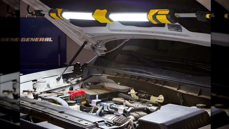 The Braun Underhood Light clamped to a car hood shining on the engine bay.