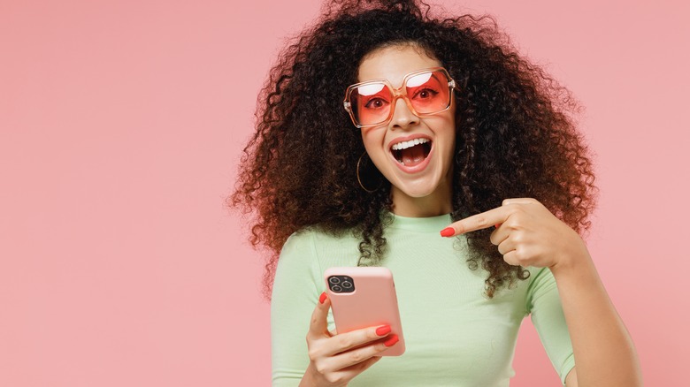 Women in mint shirt pointing at phone