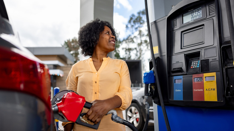 Driver filling car with gasoline using red nozzle