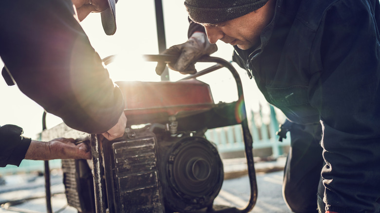Two men repairing a generator