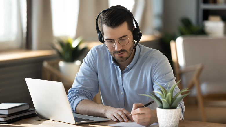 A man working at his desk using Bluetooth headphones 