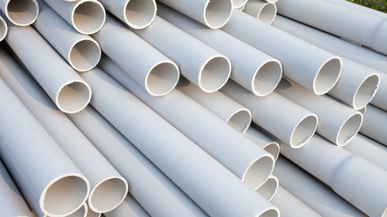 A large stack of white PVC pipes on a construction site