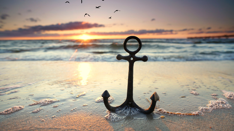 Anchor washed up on shore near a beach at sunset