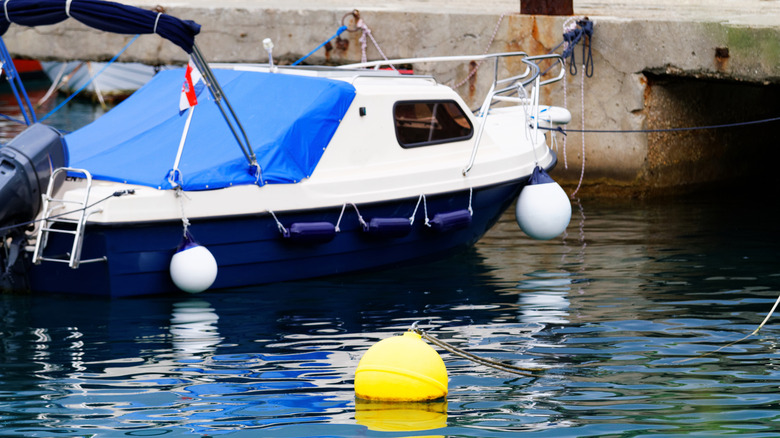 Small boat tied up to a dock with a mooring bouy in the foreground