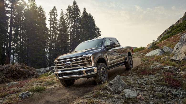 A Ford Super Duty f-250 truck driving off-road down a hill in nature.