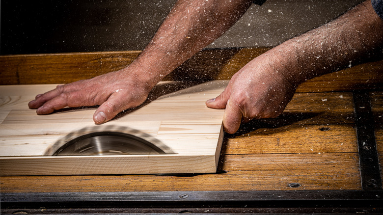 A person cutting a section of wood with a table saw