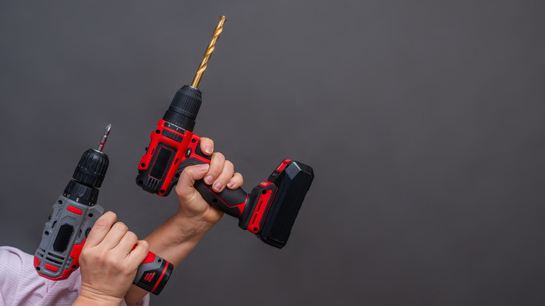 A person holding a cordless drill in each hand