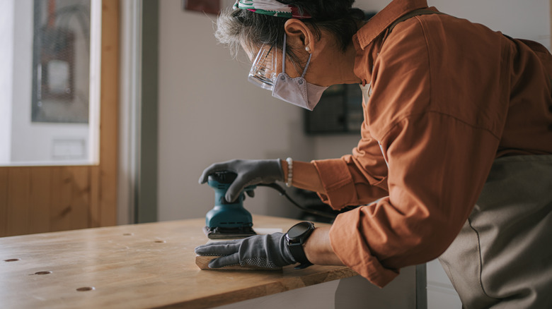 A person running a sander on a piece of wood