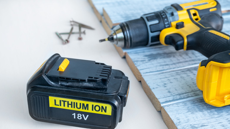 A cordless drill and its battery laying side by side