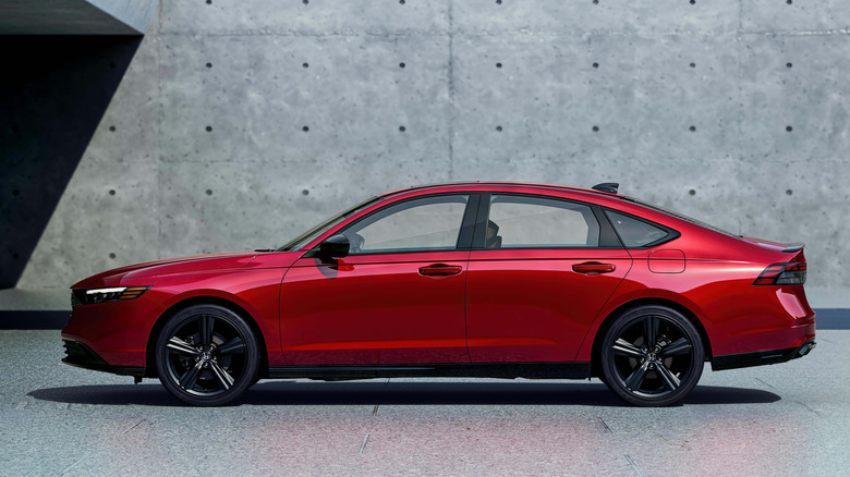 Side view of red 2026 Honda Accord parked in front of building.