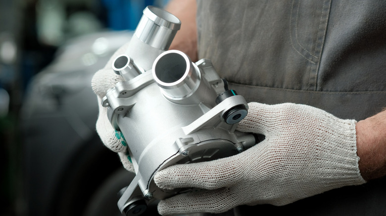 A car mechanic holding a new electric pump for the engine