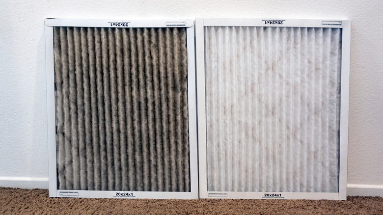 One dirty and one clean air conditioning system filter side by side on carpet