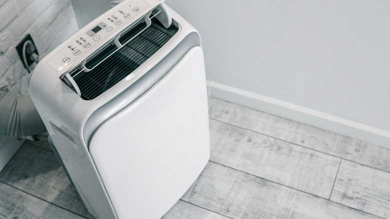 A portable air conditioner plugged into a wall socket.