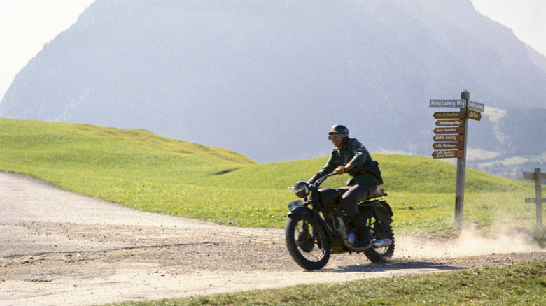 Steve McQueen riding a black Triumph TR6 Trophy on a dirt road