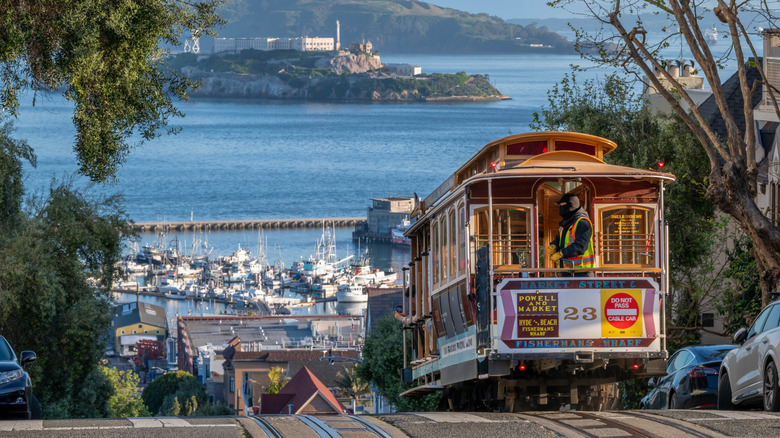 A San Francisco cable car about to descend a hill with Alcatraz Island in the background.