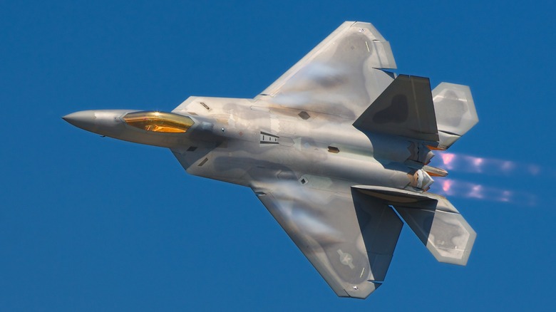 An F-22 Raptor performing at an air show over blue skies