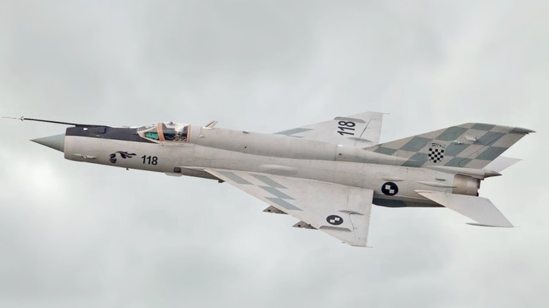 A MiG-21 flying over grey cloudy skies
