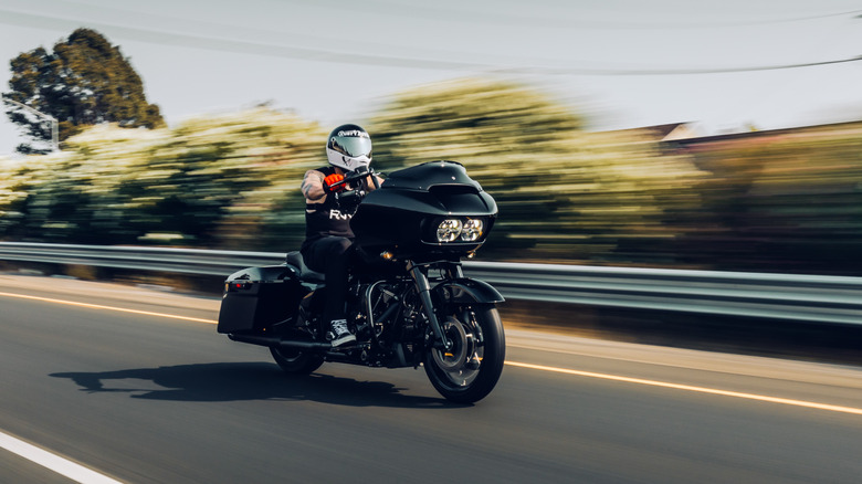 A front 3/4 dynamic shot of a person driving a Harley-Davidson cruiser down the highway.