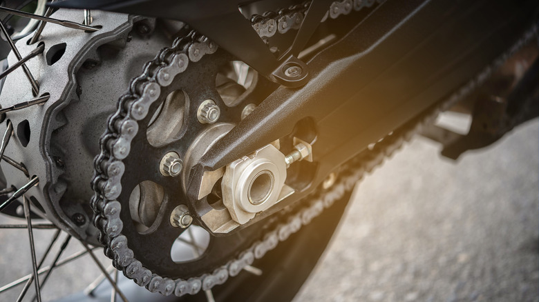 Close up of a motorbike chain drive on the rear wheel.