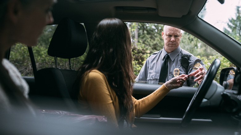 An on duty law enforcement officer inspects the driver's license of a person he has pulled over for speeding.