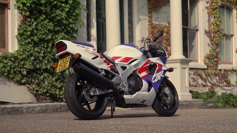 A blue and white first-generation 1996 Honda CBR900 Fireblade parked outside Charles Darwin's house.