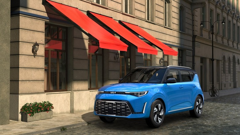 A Blue 2025 Kia Soul parked outside a shop, in the shade of a red awning