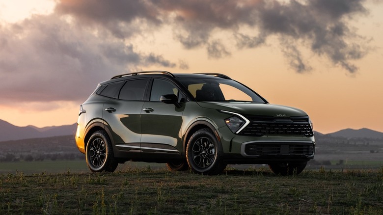 A military green Kia Sportage 2025 in a field against a dusk skyline.