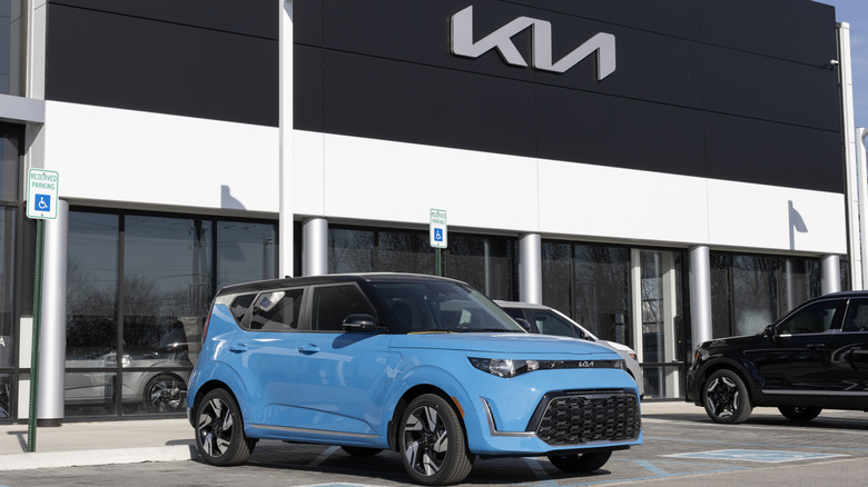A blue Kia Soul standing outside a KIA showroom