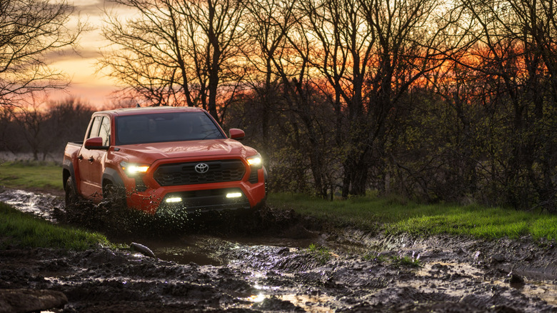 Red 2024 Toyota Tacoma i-FORCE MAX driving through mud