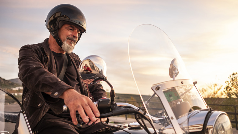 A biker on a motorcycle with a sidecar, resting after travel at sunset