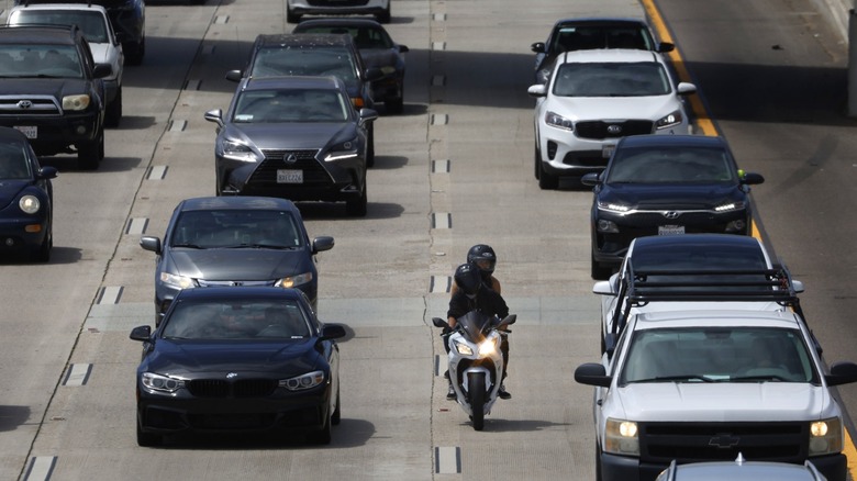 A motorcyclist lane splitting on a busy highway