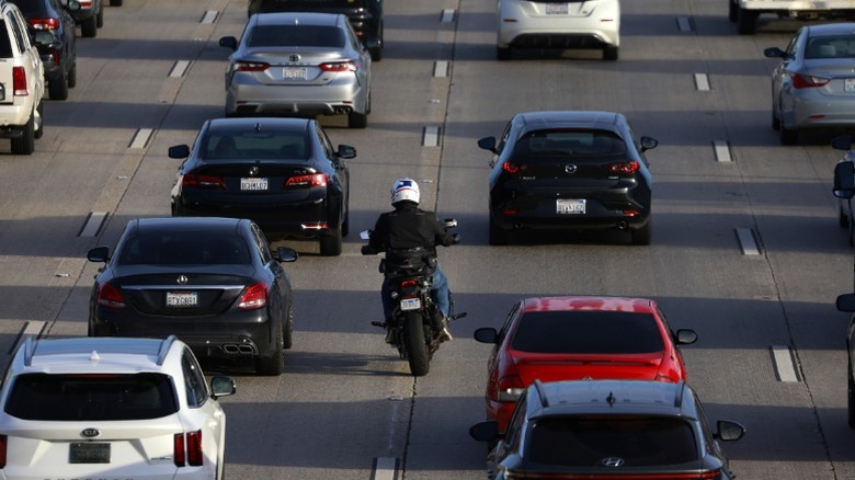 A motorcyclist lane splitting on a busy california highway